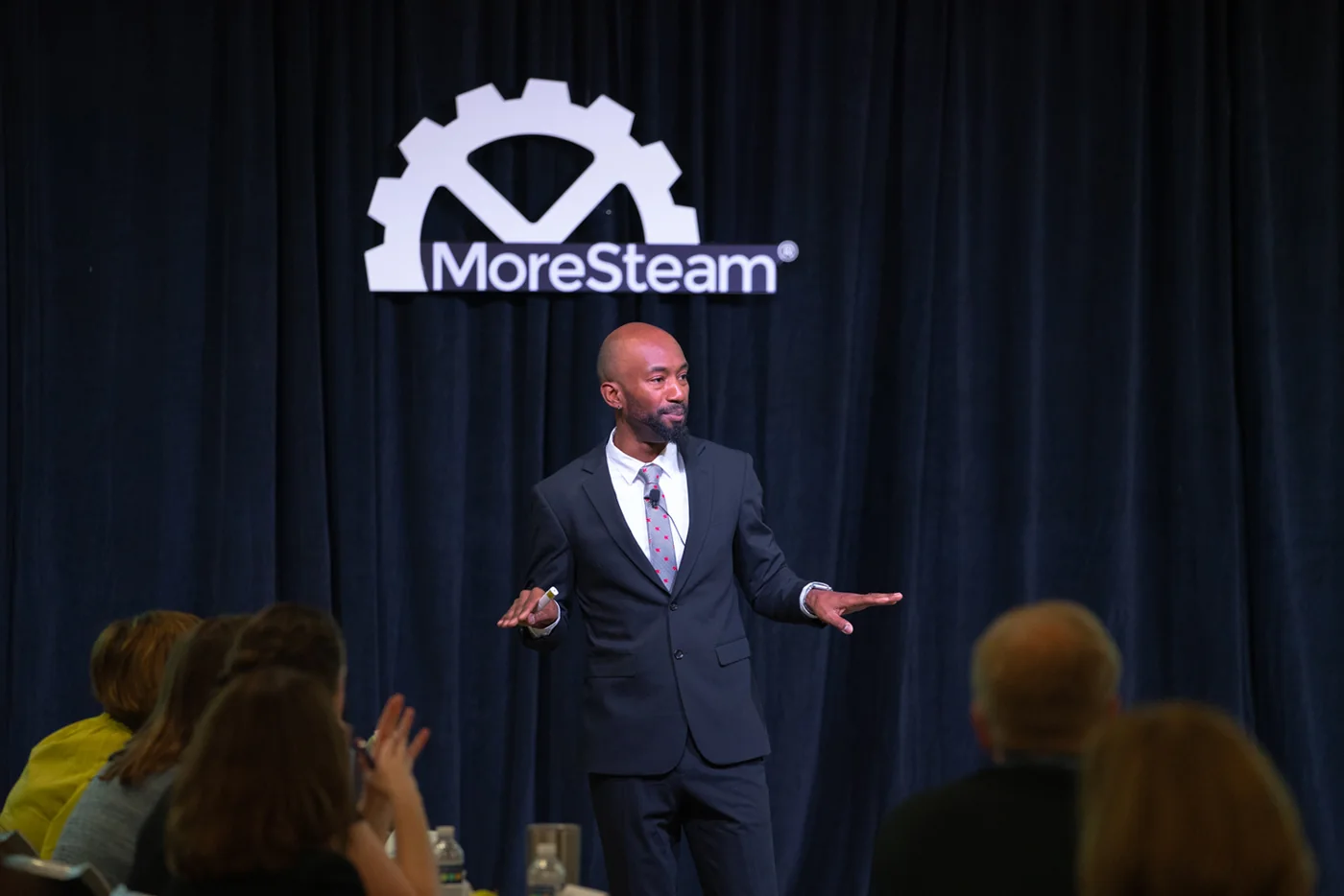 Emmanuel Aouad speaking on stage at a MoreSteam conference.